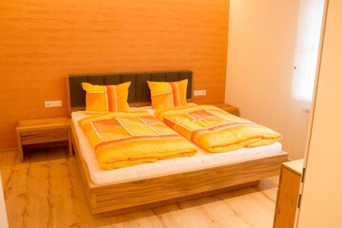 a bed with yellow and orange blankets and pillows at Appartement Montanea in Schruns-Tschagguns
