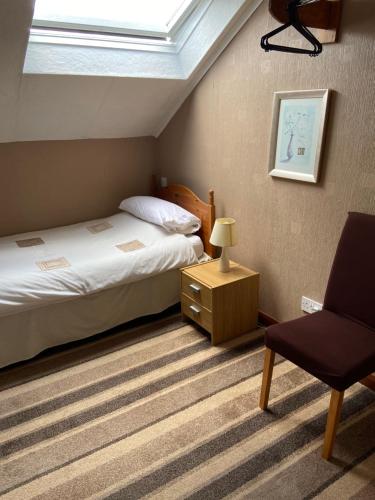 a bedroom with a bed and a chair and a window at Belhaven Private Hotel in Aberdeen