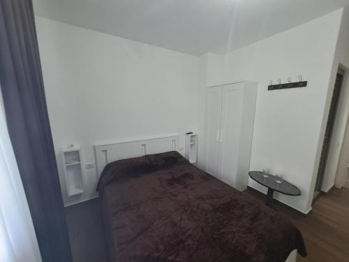 a white room with a bed and a table at Pensiunea Theo Enelid in Afumaţi