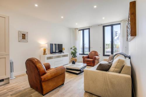 un salon avec un canapé et deux chaises et une télévision dans l'établissement Appartement GRAND CONFORT BORD DE MER Rez-de-Chaussée RESIDENCE LA VAGUE, à Houlgate