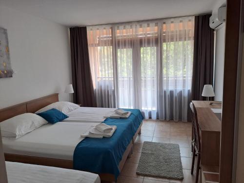 a bedroom with two beds and a desk and window at Hotel Albamaris in Biograd na Moru