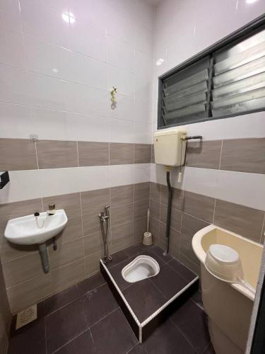 La salle de bains est pourvue de toilettes et d'un lavabo. dans l'établissement Rumah 127 - Homestay Taiping, à Simpang