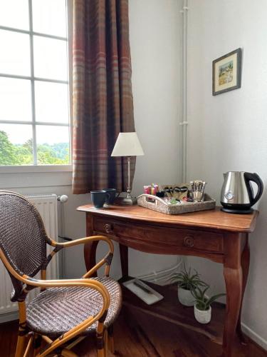 a desk with a lamp and a chair next to a window at Les Hortensias in Espoey