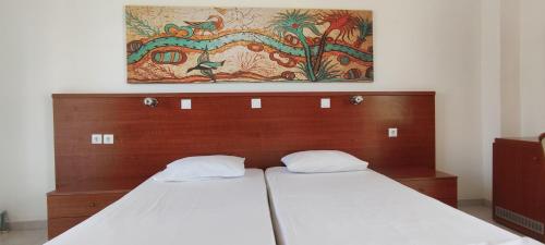 Bett mit einem Kopfteil aus Holz mit einem Gemälde darüber in der Unterkunft Elga Hotel in Kardamaina