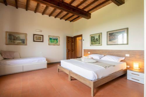 a bedroom with a large white bed and a couch at Podere La Quercia in San Gimignano