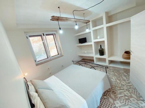 um quarto branco com uma cama e uma janela em DONNA PETRONILLA SOUTHERN HOUSE em Pianopoli
