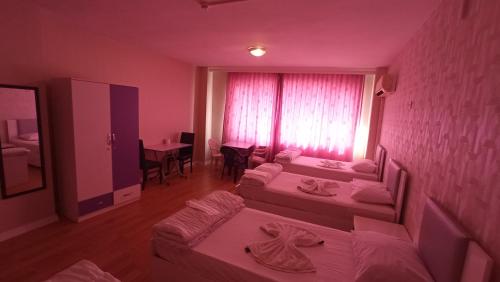 a room with two beds and a table and a window at ESEN OTEL in Antalya