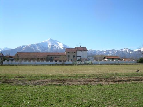 a field with a building and mountains in the background at B&B CM Ranch in Cuneo