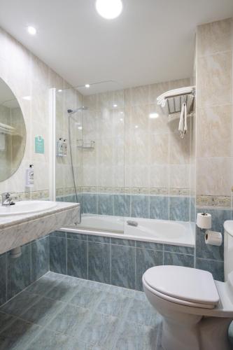 a bathroom with a tub and a toilet and a sink at Hostal Alda Río Duero in Soria
