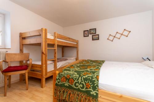 ein Schlafzimmer mit einem Etagenbett und einem Stuhl in der Unterkunft Villa Catia in Moena