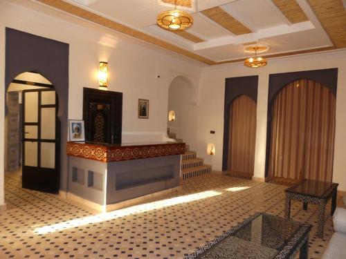 a room with a lobby with a fireplace and a table at Riad La Luna in Merzouga
