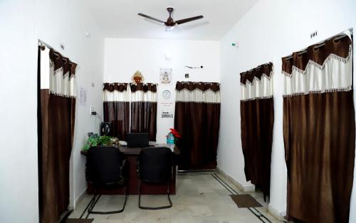 Zimmer mit Tisch, Stühlen und Vorhängen in der Unterkunft SHIVAY Guest House in Deoghar