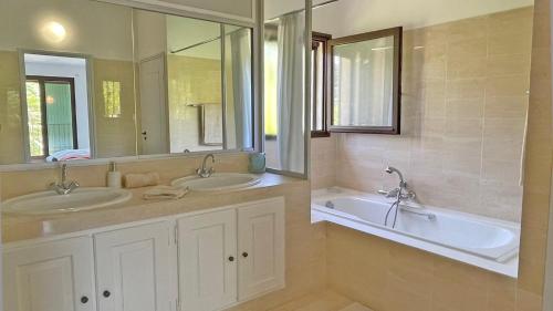une salle de bain avec deux lavabos, une baignoire et un miroir dans l'établissement Villa Morigati - Les Palmiers, à Grimaud