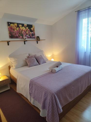 a bedroom with a large white bed with purple sheets at Apartment Aria in Vir