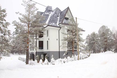 une maison blanche dans la neige avec des arbres dans l'établissement Apartman Lav, à Divčibare