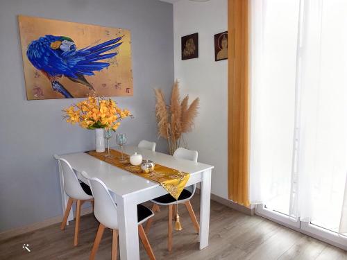 a white dining room table with chairs and a blue bird painting at Chic et douillet in Perpignan