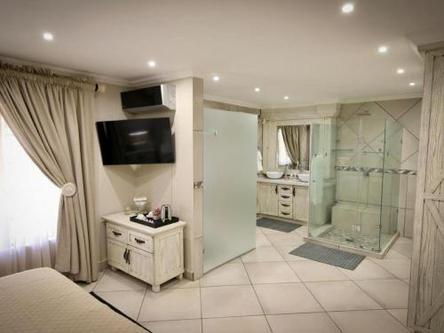 a large bathroom with a shower and a television at Decollage Estate in Polokwane