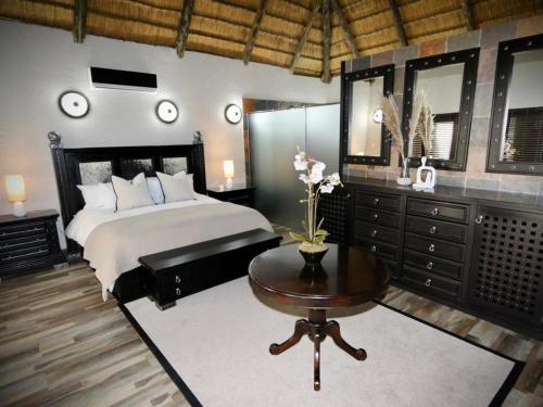 - une chambre avec un lit, une table et des miroirs dans l'établissement Decollage Estate, à Polokwane