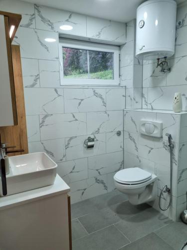 a white bathroom with a toilet and a sink at Private beach holiday home Ilan in Kulen Vakuf
