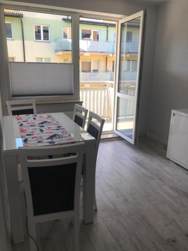 a dining room with a table and chairs and a balcony at Ustka Apartament Na Wydmie in Ustka