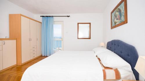 a bedroom with a large white bed with a blue headboard at Apartments Maria in Povlja