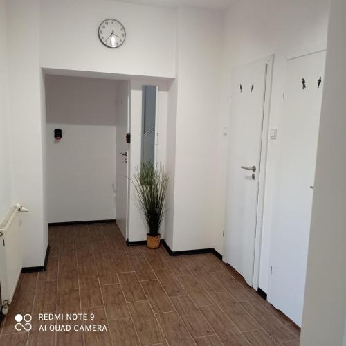 a hallway with white walls and a clock on the wall at Hostel Wiśniowa 55 in Wrocław