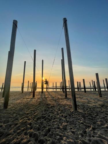 a person standing on a beach with poles at Hart van Petten in Petten