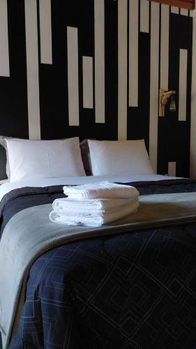a bed with white pillows and black and white stripes at Pousada Sítio Vale das Olivas in Aiuruoca