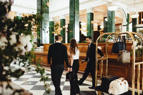 a group of people walking through a store with luggage at The Ned in London