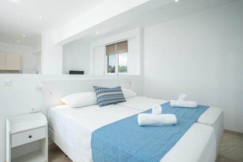 Un dormitorio blanco con una cama con toallas. en VOULA APARTMENTS, en Faliraki