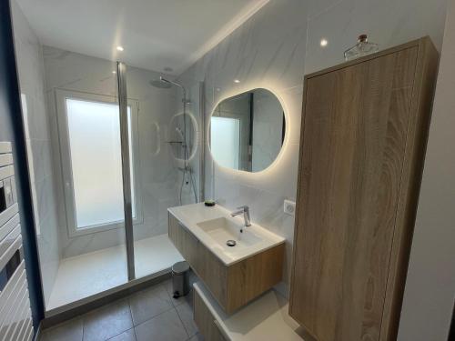 une salle de bain avec un lavabo, une douche et un miroir dans l'établissement Élégant logement avec vue sur l'océan, à La Baule