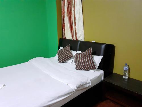 a bedroom with a bed with three pillows on it at Ambience House in Pātan