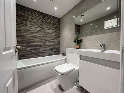 La salle de bains est pourvue de toilettes, d'un lavabo et d'une baignoire. dans l'établissement Three Bed Townhouse with Parking, à Telford