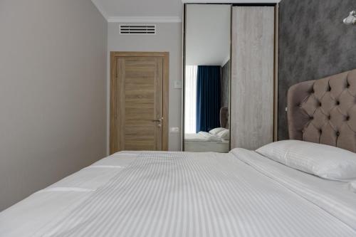 a bedroom with a white bed and a mirror at Panorama Kvariati in Kvariati