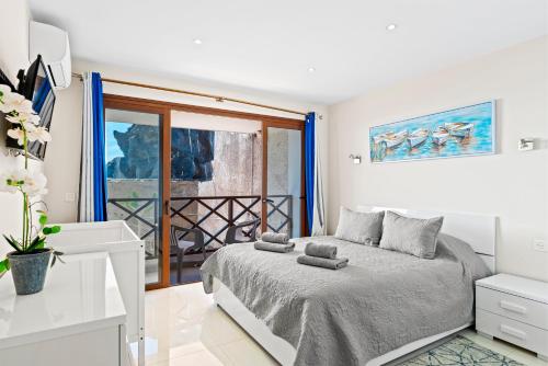 a white bedroom with a bed and a window at Duplex Ocean View Apartment in Neptuno in Puerto de Santiago