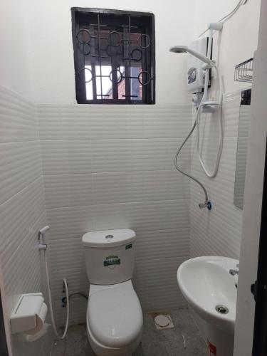 a bathroom with a toilet and a sink and a window at Jogoo rooms in Dar es Salaam