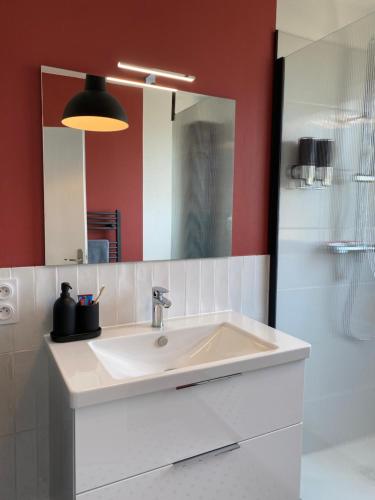 uma casa de banho com um lavatório branco e um espelho. em Le Cinquième em Bressuire