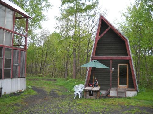 a small cabin with a table and an umbrella at Niseko Shirokuma Cottage in Niseko