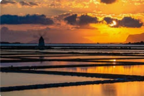 una puesta de sol sobre una playa con puesta de sol en Casa vacanze tra la campagna e il mare, en Marsala