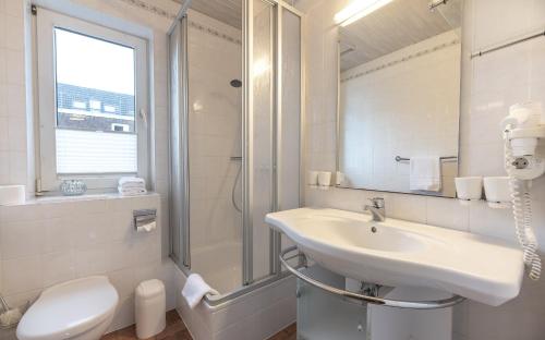 een witte badkamer met een wastafel en een douche bij Haus in der Innenstadt 'Sylt', Große Straße in Wyk auf Föhr