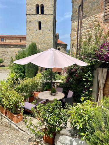 a table and chairs with an umbrella in front of a building at La Magione dei Todaro in Borgo a Buggiano
