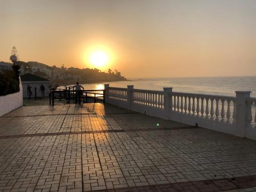 a man sitting at a bench watching the sunset at RIBERA PLAYA ALHAMAR in Sitio de Calahonda