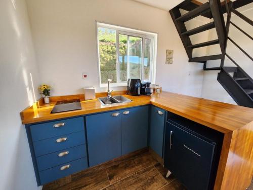 uma cozinha com armários azuis e um balcão de madeira em O Chalezinho em Serra Negra