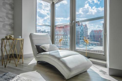 グダニスクにあるCITYSTAY Ambra Waterlane Apartmentの大きな窓のある客室で、白い椅子が備わります。