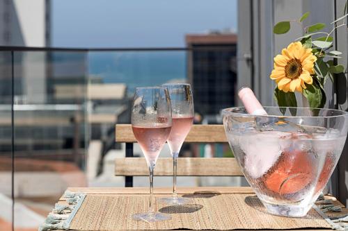 dos copas de vino y un jarrón de flores en una mesa en 19 Nineteen Suites - Espinho, en Espinho