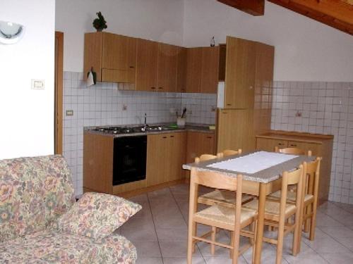 - une cuisine avec des placards en bois, une table et un canapé dans l'établissement Casa vacanze Rosa 9, à Brez