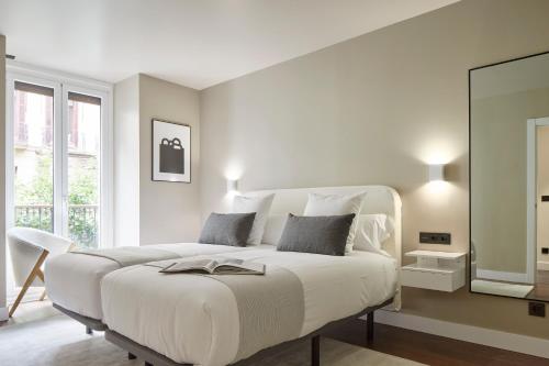 a bedroom with a white bed with a book on it at Elkano by FeelFree Rentals in San Sebastián