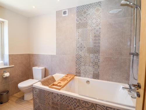 a bathroom with a tub and a toilet at Keepers Cottage in York
