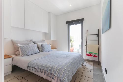 a white bedroom with a bed and a window at Casa Alegra in Carvalhal