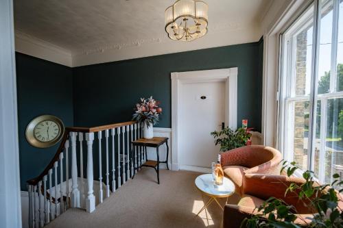 a living room with a couch and a clock on the wall at The Bramley House Hotel in Chatteris